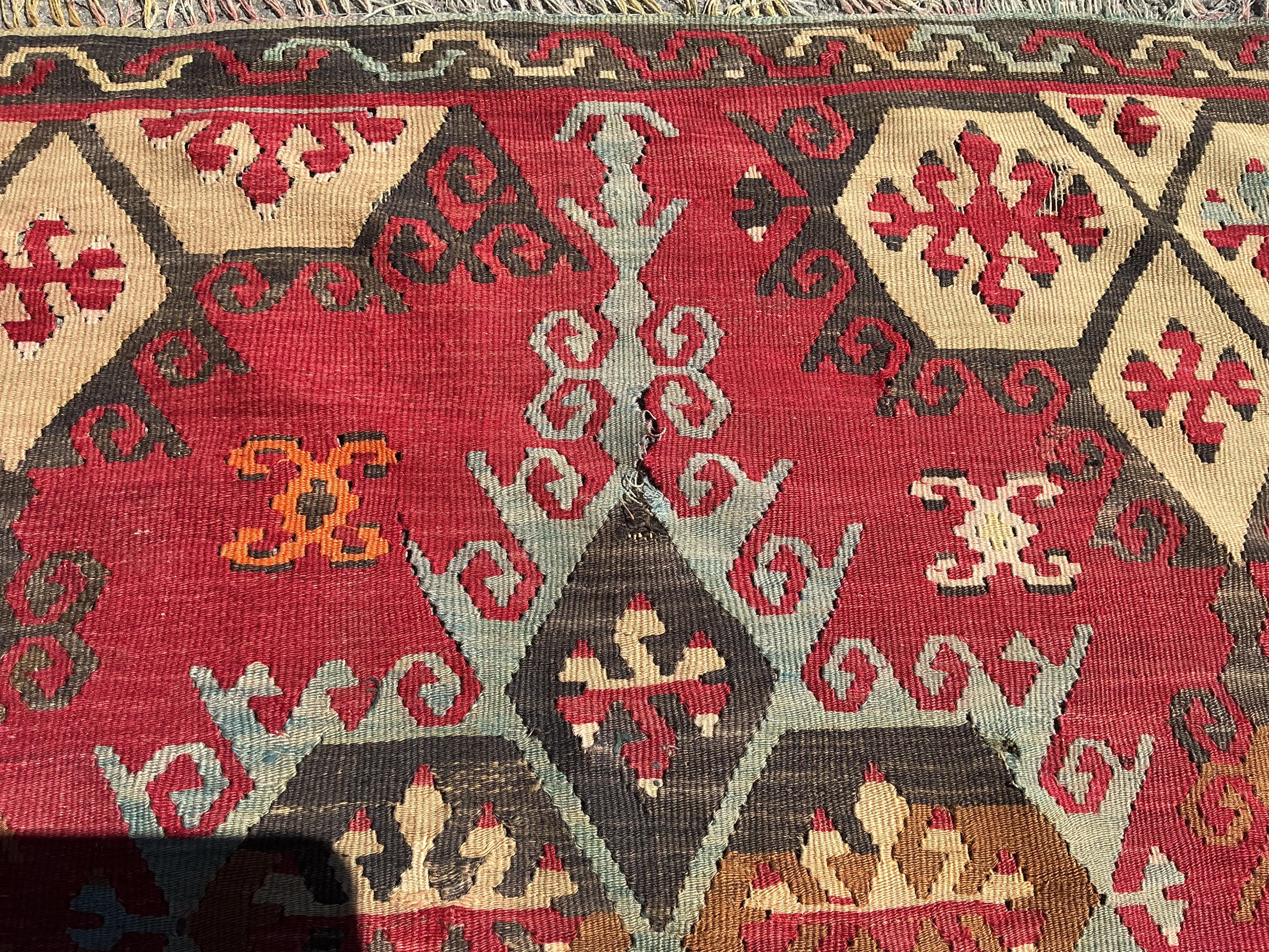 A Turkish Anatolian Kilim polychrome flatweave carpet, woven with geometric lozenges, on a pink field, 350 x 273cm